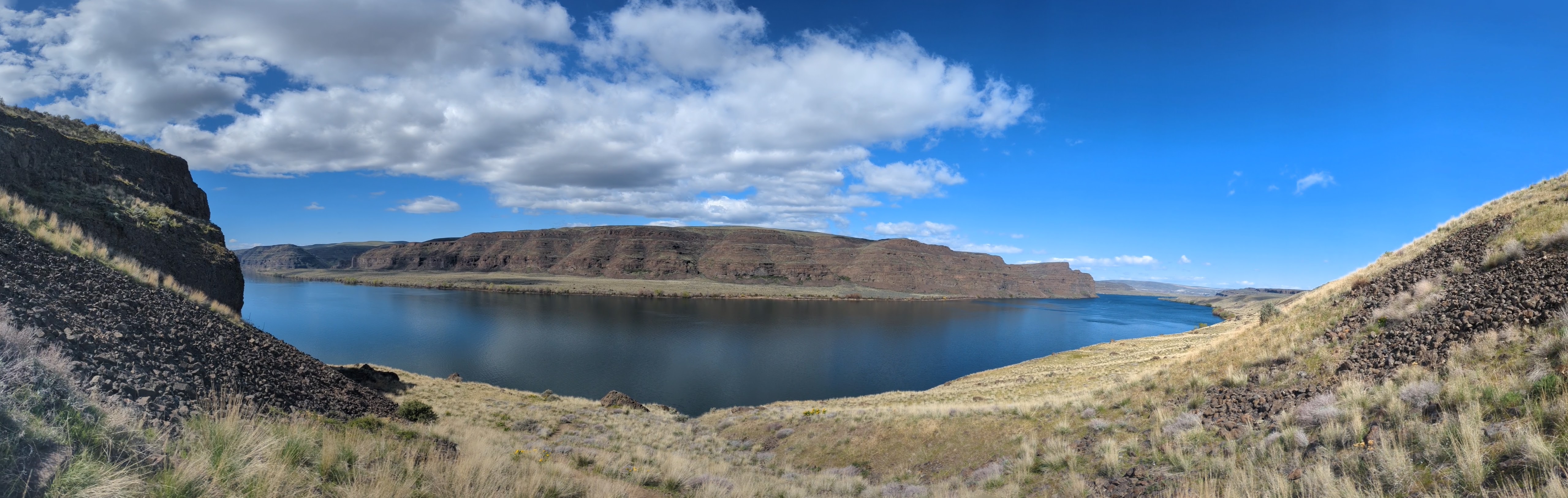 A panorama of a river with steep cliff faces on the opposite side