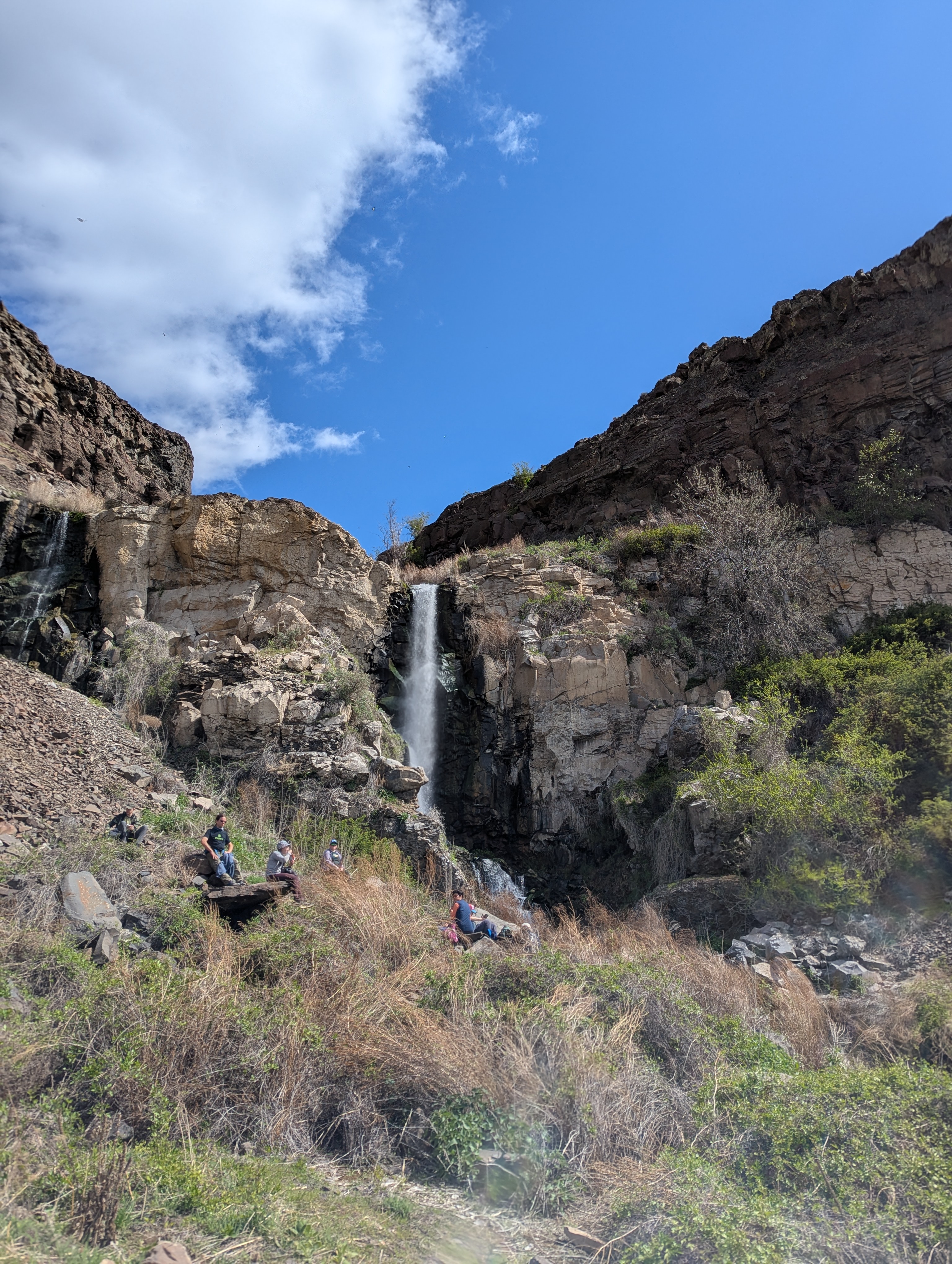 A waterfall, with many people sitting around it
