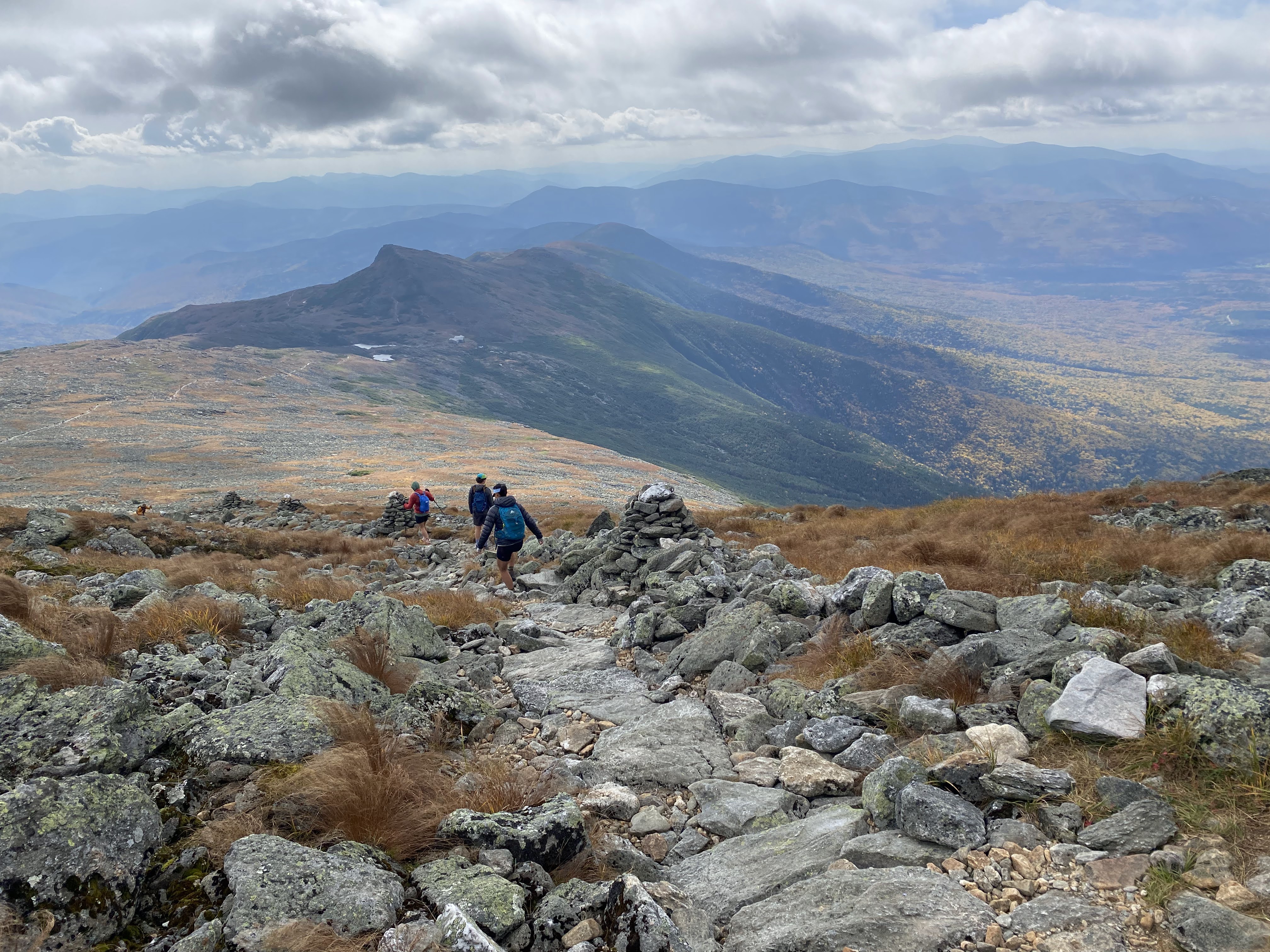 The group descending down a trail, a lake and a hut off in the distance