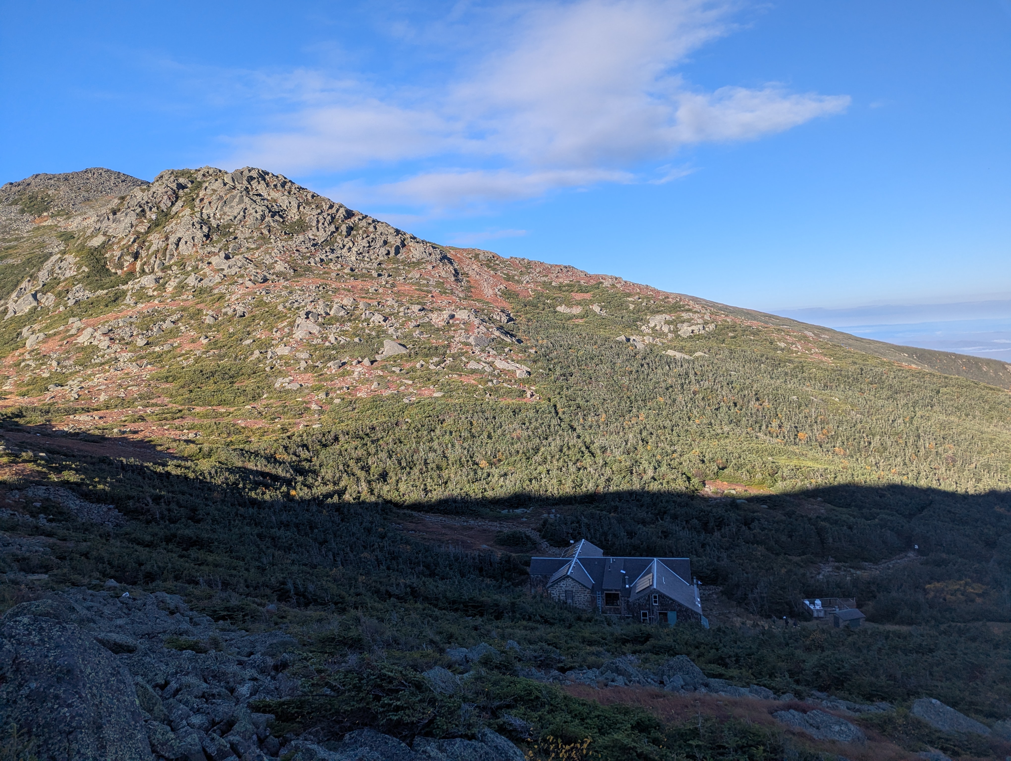 A view of Madison Hut in shadow, above it John Quincy Adams and Mount Adams