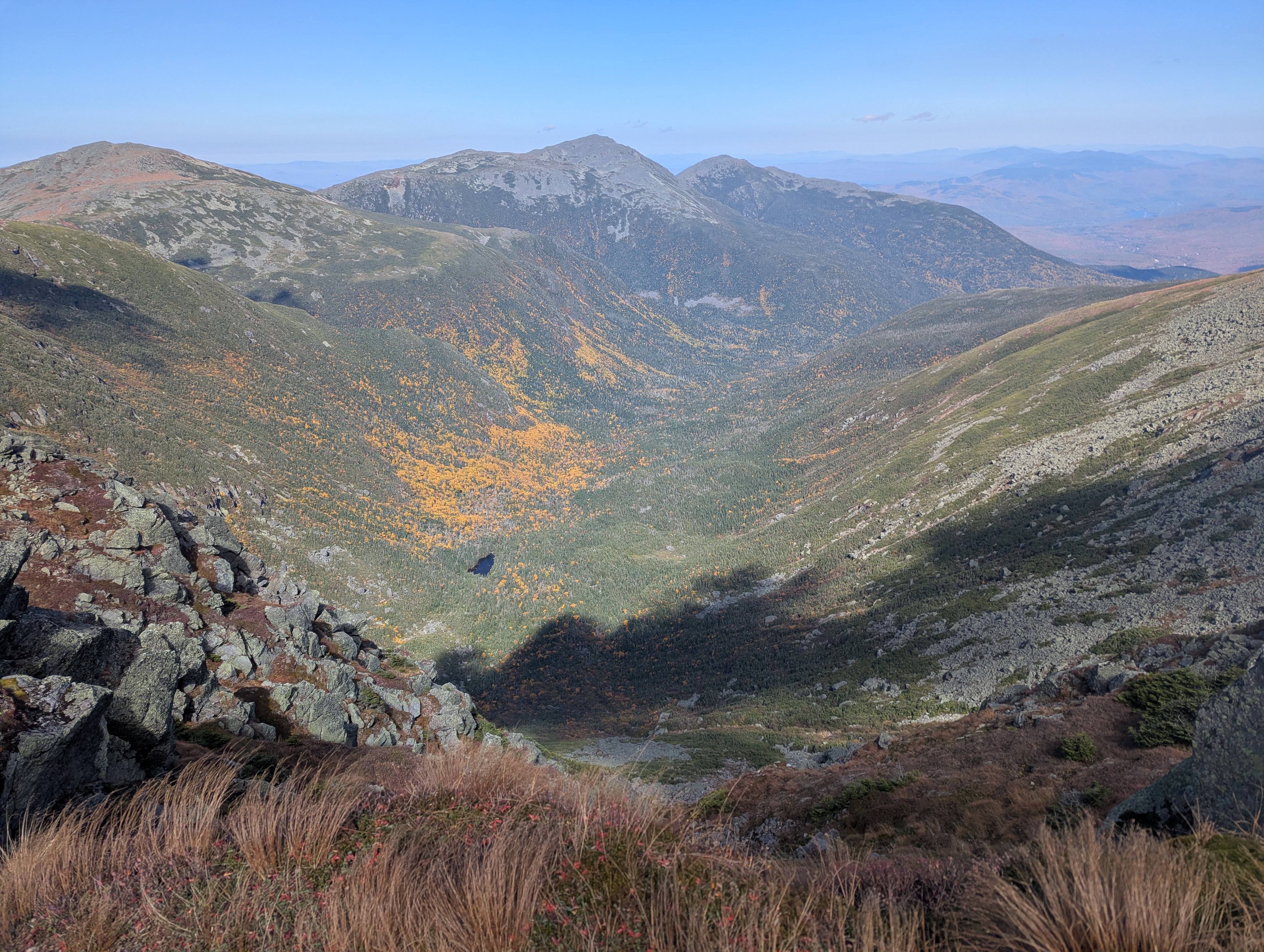 A view of a valley, with a small lake and yellow trees scattered about