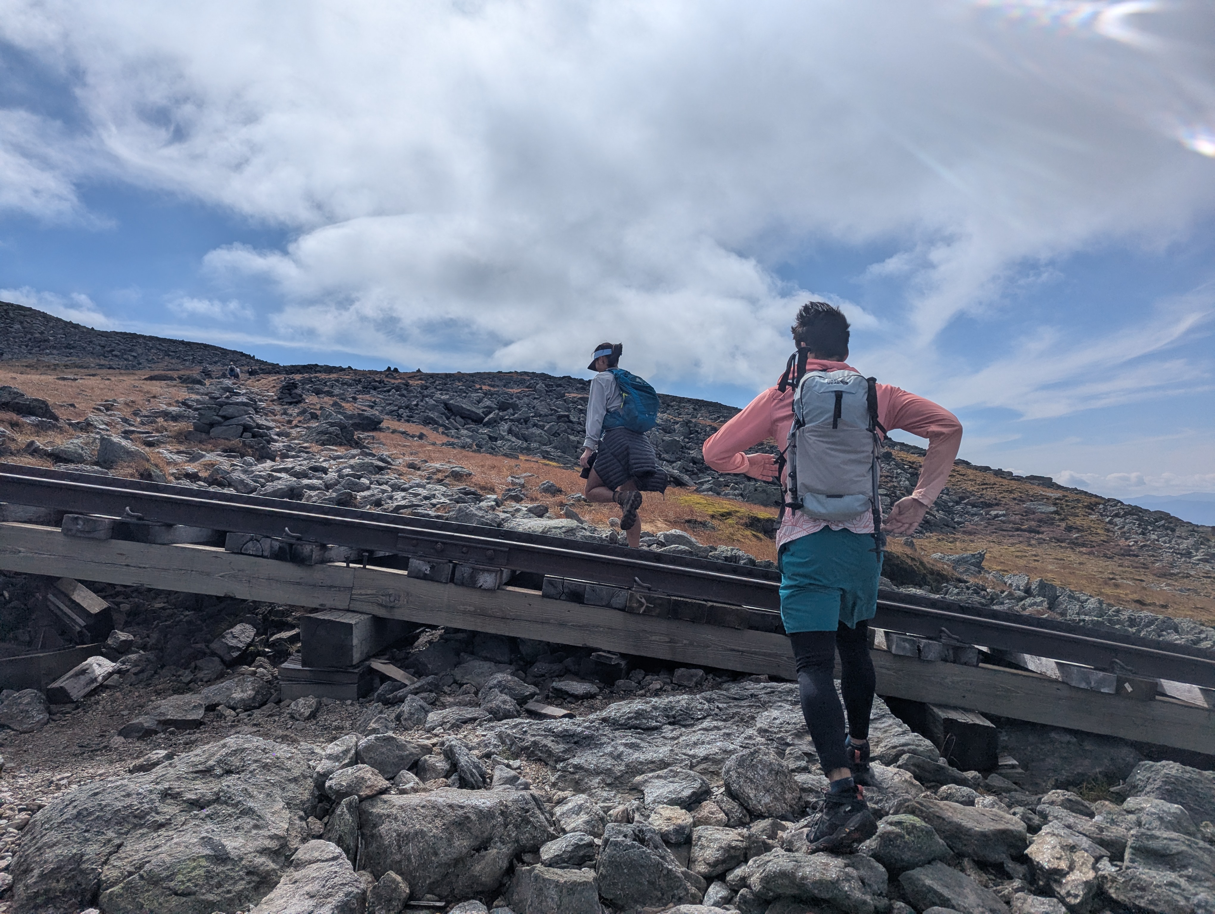 Hikers crossing railroad tracks that run steeply up a mountain