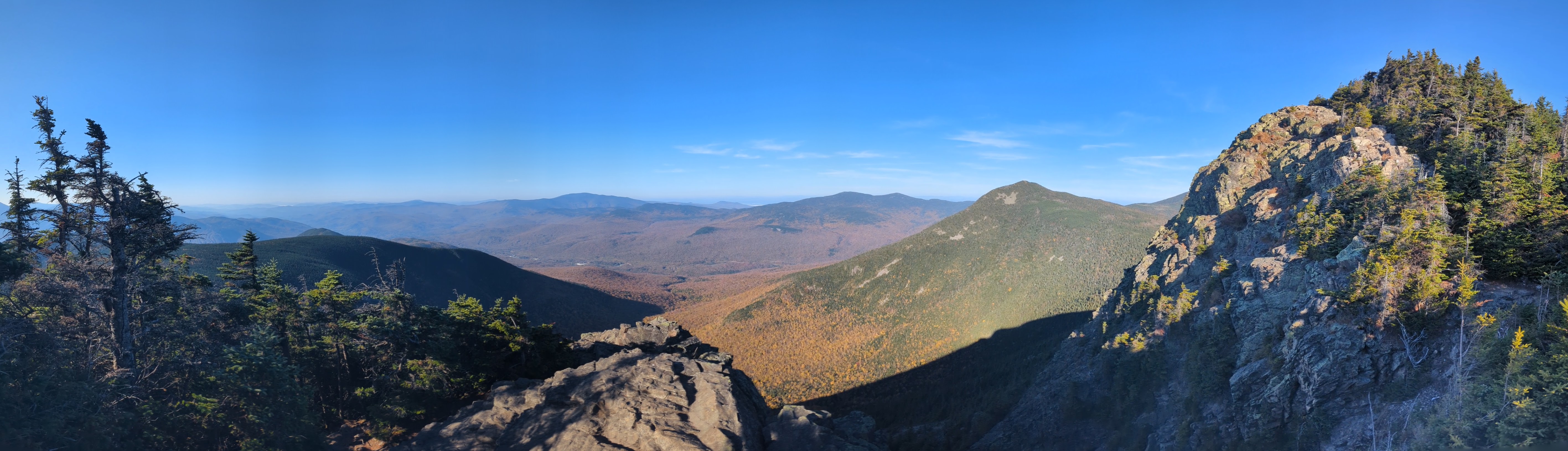 A panoramic view of colorful trees below, with a ridgeline off to the right