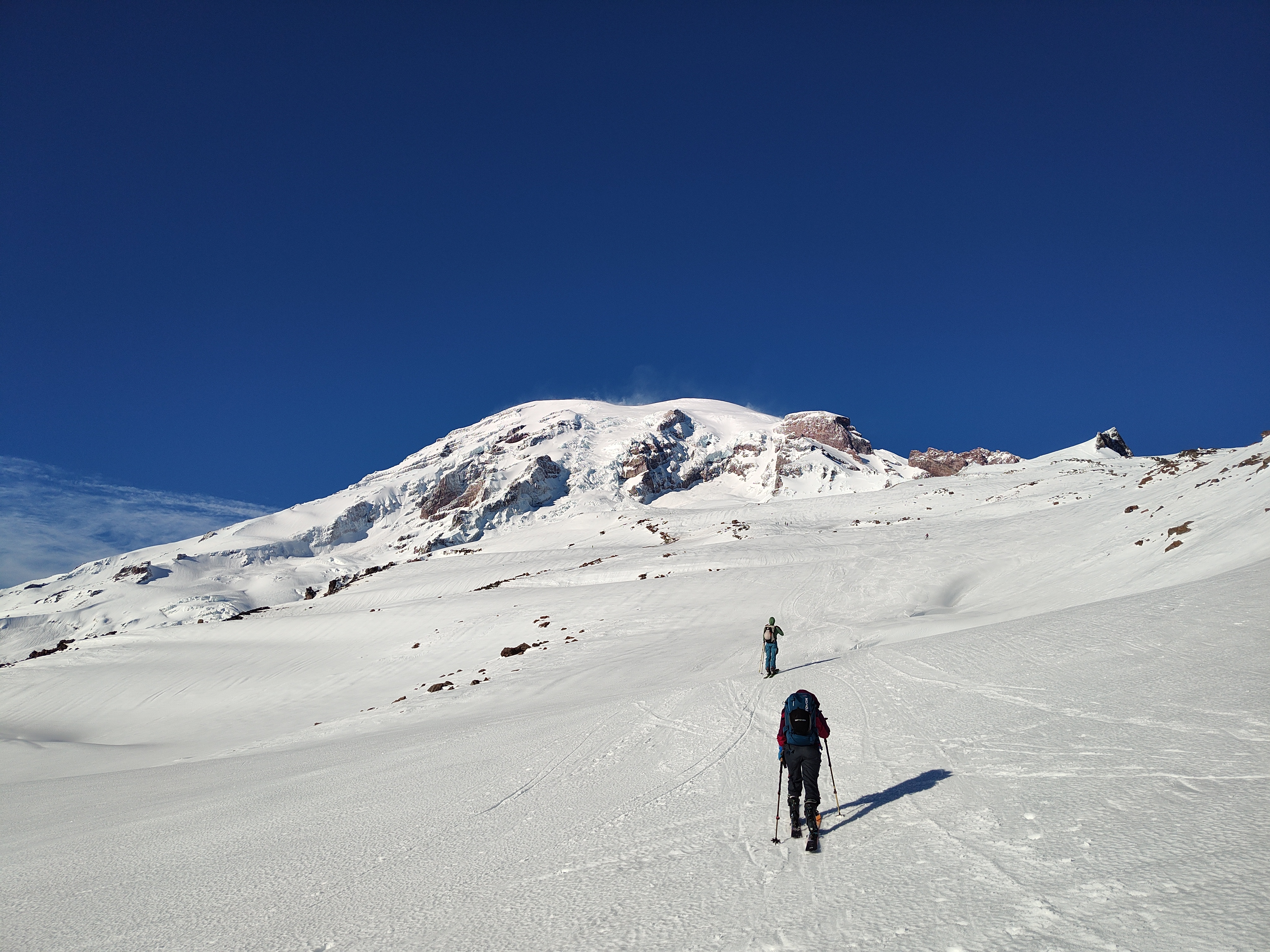 Skiers skinning up open slopes below Tahoma